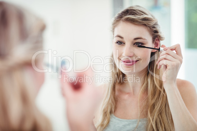 Smiling woman applying mascara
