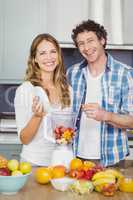 Portrait of smiling couple preparing fruit juice