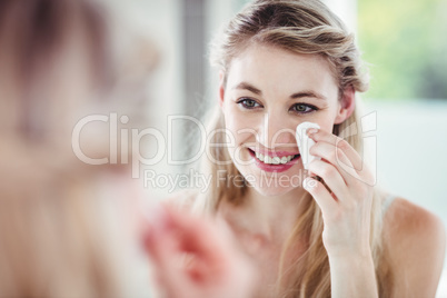 Happy young woman applying blush