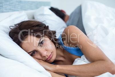 Portrait of serious woman lying on bed
