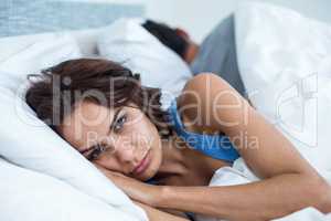 Portrait of serious woman lying on bed
