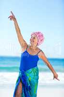 Pretty mature woman raising her arms on the beach
