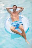 Happy shirtless man relaxing on inflatable ring