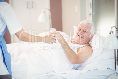 Nurse giving water glass to senior man