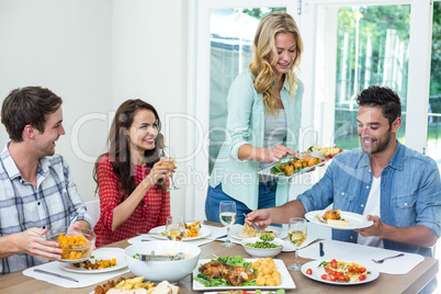 Smiling woman serving food to friends