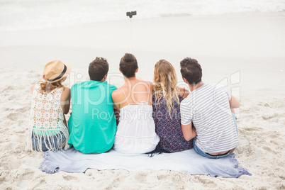 Rear view of friend taking a selfie on the beach