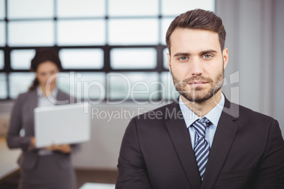 Confident young businessman while colleague in background