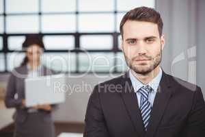 Confident young businessman while colleague in background