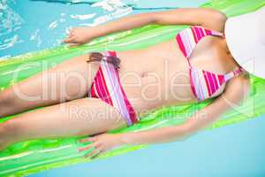 Mid section of a woman in bikini lying on air bed in swimming po