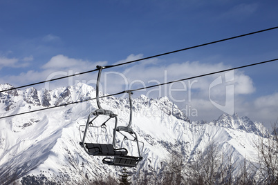 Chair lift in snowy mountains at nice sunny day