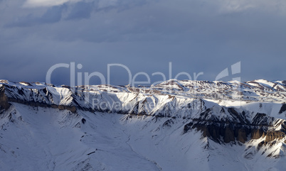 Sunlight winter mountains and dark clouds at evening