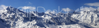 Panoramic view on snowy mountains in sunny day