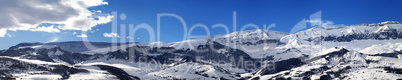 Panoramic view on snowy mountains at nice sun day