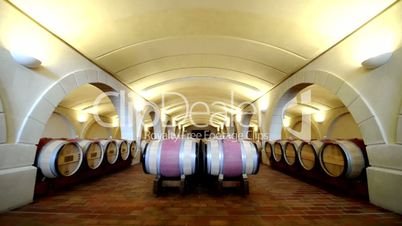 Long shot of a wine cellar with wood barrels and arches. Bordeaux, France.