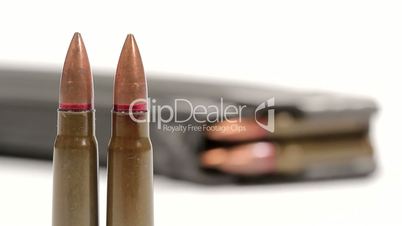 AK-47 ammunition. Defocus from two of upright bullets in the front to a lying full magazine in the back.