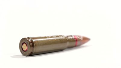 AK-47 ammunition. Defocus on a lying single bullet's bottom. From the front to the back. White background.