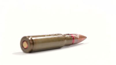 AK-47 ammunition. Defocus on a lying single bullet's bottom. From the back to the front. White background.