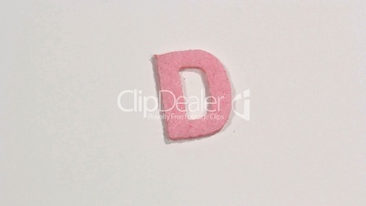 Felt letter “D” on white background. Defocus.