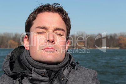 Mann mit geschlossenen Augen entspannt am See