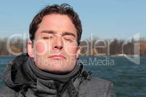 Mann mit geschlossenen Augen entspannt am See