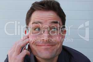 Mann mit Brille macht lustige Grimasse beim Telefonat