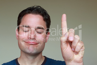 Mann mit erhobenem Zeigefinger schaut zufrieden mit geschlossenen Augen