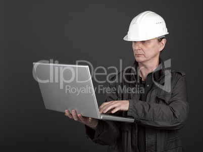 Worker in black shirt and suit holding a laptop