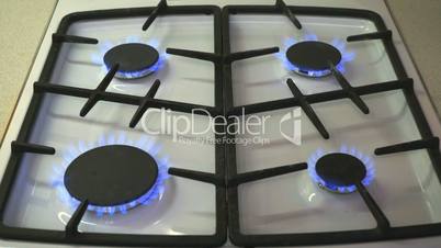 Four gas burners burn blue flame on a gas stove