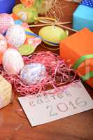 Easter with eggs in nest and yellow tulips over blue wooden table. Top view