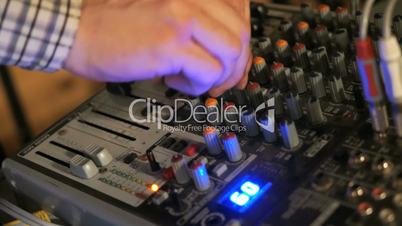 DJ works on the mixer console in night club