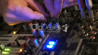 DJ works on the mixer console in night club