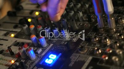 DJ works on the mixer console in night club