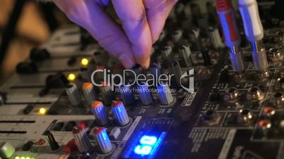 DJ works on the mixer console in night club