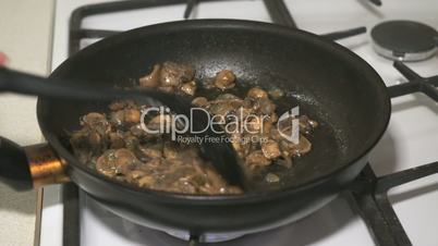 The mix of mushrooms is fried in a black pan