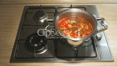 Steel pan with beet soup is on the stove