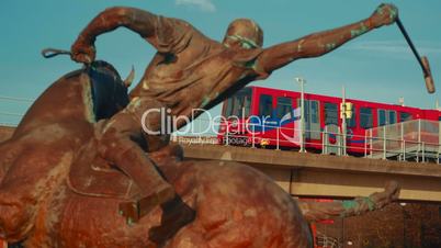 Departing DLR Train Framed by a Polo Player Statue