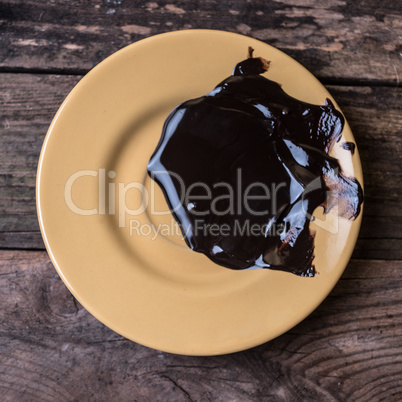 Melted dark chocolate on the yellow plate