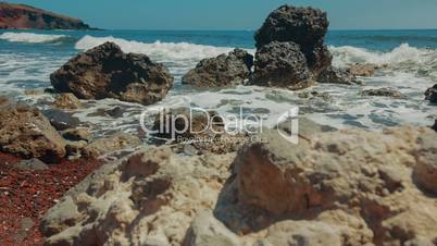 Slider Shot of Mediterranean Volcanic Beach with Red Sand and Surf Hitting the Rocks