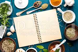 culinary background and recipe book with various spices on wooden table