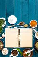 culinary background and recipe book with various spices on wooden table