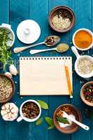 culinary background and recipe book with various spices on wooden table