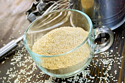 Flour sesame in cup with sieve on board