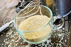 Flour sesame in cup with sieve on board