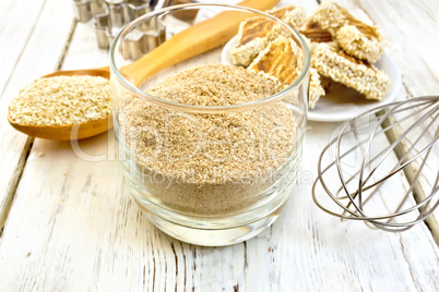 Flour sesame in glassful with spoon on board