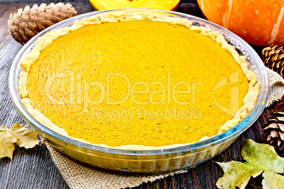 Pie pumpkin in glass pan on dark board