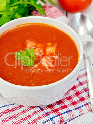 Soup tomato with parsley on napkin and spoon