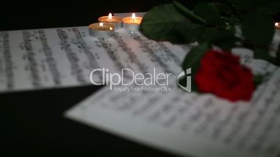 Three beautiful roses with book, music notes, glass and burning candle