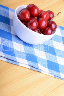 Red ripe cherries in a white bowl