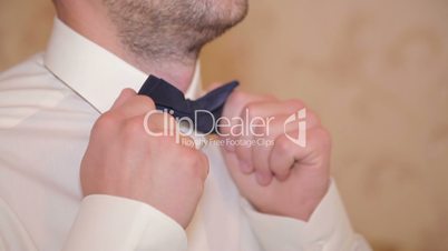 The groom adjusts his tie. close-up. slowmotion