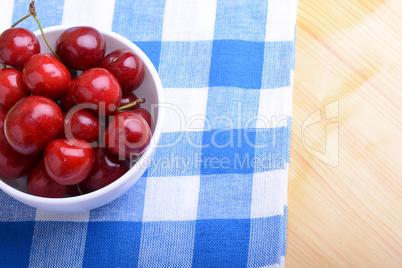 Red ripe cherries in a white bowl